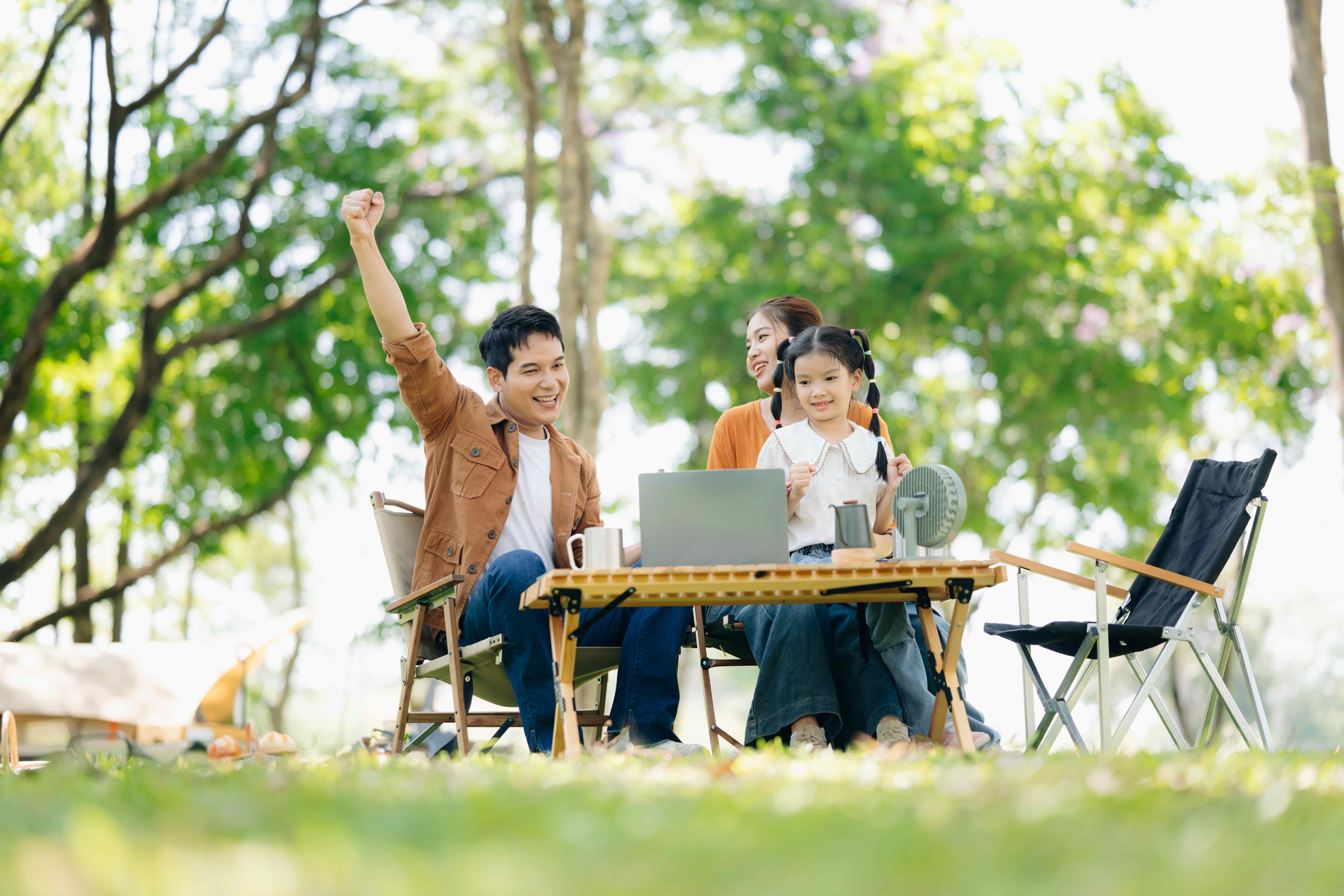 Family relaxing outdoors with a laptop