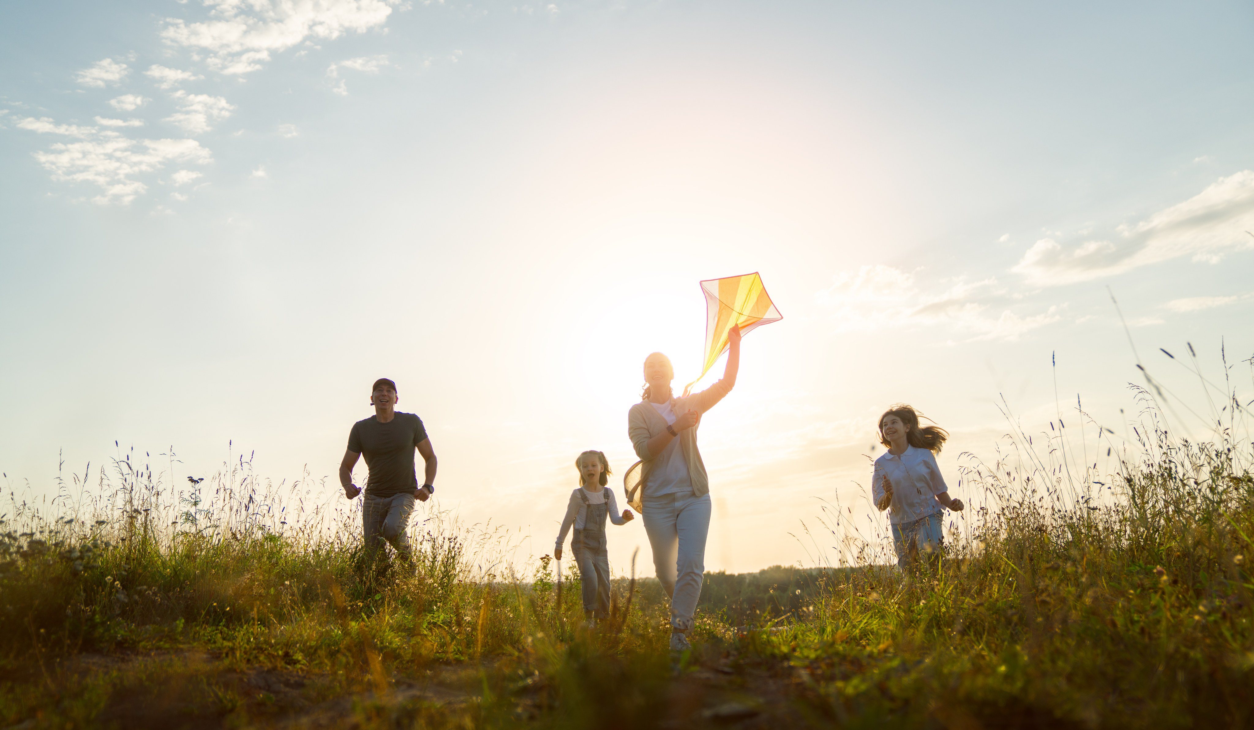 Family running through a field at sunset